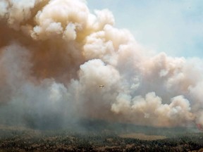 Charges have been laid against a 22-year-old Nova Scotia man for lighting a fire last May that grew to become the largest wildfire in the province's history. In this aerial image, an aircraft, centre, flies near a wildfire burning near Barrington Lake in Shelburne County, N.S., on Wednesday, May 31, 2023.