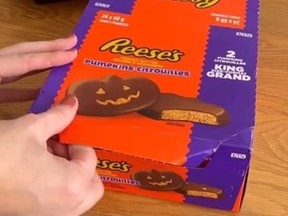 Screenshot of hands opening up box of Reeses Peanut Butter Pumpkins.