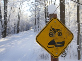 This sign on a trail shows snowmobiles and ATV share the same paths in the winter time.