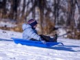 A boy is heading downhill in a toboggan.