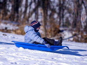 A boy is heading downhill in a toboggan.