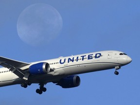 A United Airlines Boeing 787 approaches for landing in Lisbon, Sept. 2, 2023, with the setting moon in the background.