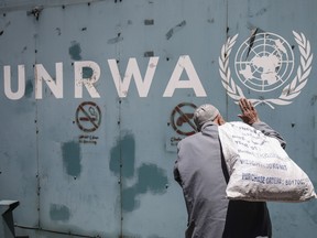UNRWA symbol on a wall with a man in front with a sack over his back