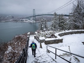 A person walks down the snow-covered steps at Prospect Point near the Lions Gate Bridge as snow falls in Vancouver on Saturday, Feb. 13, 2021.