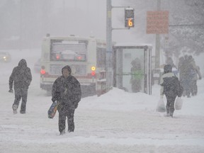 Pedestrians cross a snow-covered street in Toronto on Friday, Feb. 8, 2013.