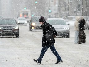 A person crosses a street as snow falls in Montreal, Sunday, January 7, 2024. Environment Canada has issued weather alerts for large parts of Ontario and Quebec as a winter storm is expected to bring up to 40 centimetres of snow in some regions.
