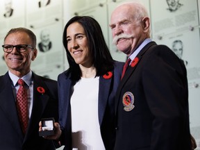 Caroline Ouellette, centre, receives her Hockey Hall of Fame ring from Mike Gartner, left, and Lanny McDonald.