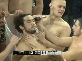 Members of the Oakland University swim team get haircuts during a basketball.