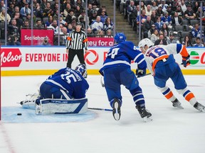 Pierre Engvall of the New York Islanders scores against Maple Leafs goalie Ilya Samsonov as Morgan Rielly looks on.