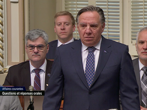Premier François Legault stands in silence as MNAs chuckle about his use of the word "cool" while lamenting the popularity of anglicisims on Feb. 8, 2024.