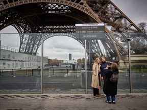 Pedestrians take a picture next to the Eiffel Tower, and a board (Top R) informing visitors that the monument is closed as staff go on strike in Paris on February 19, 2024. (KIRAN RIDLEY/AFP via Getty Images)