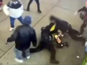 This image taken from video provided by the New York City Police Department shows police officers confronting a group near New York's Times Square, Jan. 27, 2024, bringing a man in a bright yellow coat down to the sidewalk and the chaotic scene that unfolds as at least half a dozen bystanders are seen kicking at the officers, then trying to pry them off the man.