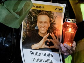 A person holds a candle and a portrait of late Russian opposition leader Alexei Navalny, who died in a Russian Arctic prison, as people gather at a makeshift memorial in downtown Zagreb on Feb. 23, 2024.