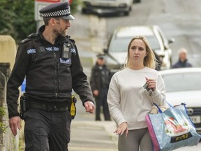 A police officer speaks to a member of the public after homes were evacuated when a suspected Second World War explosive device was discovered in a garden on St. Michael Avenue in Plymouth, England, Thursday Feb. 22, 2024.