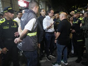 The Mayor of Medellin, Federico Gutierrez, center, talks with one of his municipal workers as he visits police patrolling Lleras Park to enforce a curfew on minors in Medellin, Colombia, Friday, Feb. 2, 2024.