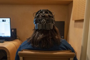 Emily Hollenbeck, a deep brain stimulation therapy patient, demonstrates an EEG device that records brain activity as she reacts to short videos at Mount Sinai's Q-Lab in New York on Dec. 20, 2023.