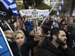 A protester raises a crucifix during a rally against same-sex marriage, at central Syntagma square, in Athens, Greece, Sunday, Feb. 11, 2024.