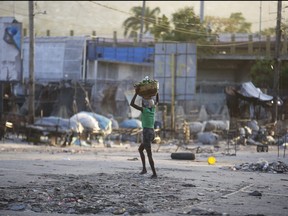 A woman crosses a street after clashes between police and gunmen at the Portail neighbourhood of Port-au-Prince, Haiti, Thursday, Feb. 29, 2024.