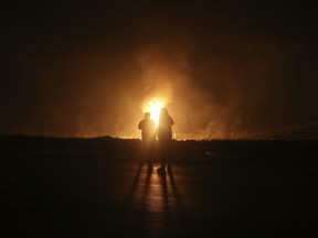 Two men look at flames after a natural gas pipeline explodes outside the city of Boroujen in the western Chaharmahal and Bakhtiari province, Iran, in early Wednesday, Feb. 14, 2024.