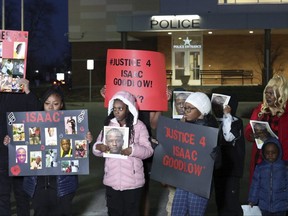 Relatives of Isaac Goodlow hold signs up during a news conference outside Carol Stream police headquarters on Monday, Feb. 12, 2024.