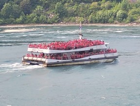People in red ponchos ride a Niagara City Cruises boat on the Niagara River.