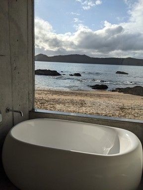 The large window in the bathroom of a suite at Den Paku The Beachfront MIJORA blurs the boundaries between the inside and outside.