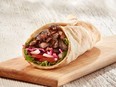 Pita wrap on wood cutting board.