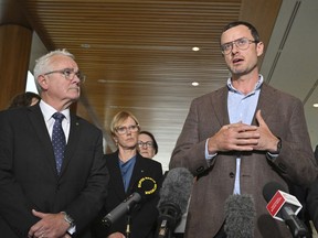 Andrew Wilkie, left, and Julian Assange's brother Gabriel Shipton, right, speak to the media