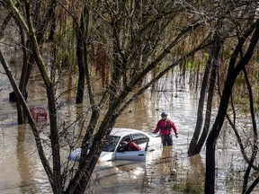 Search and rescue workers investigate a car surrounded by floodwater as heavy rains caused the Guadalupe River to swell, Sunday, Feb. 4, 2024, in San Jose, Calif. The vehicle was uninhabited.