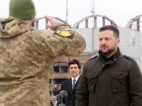 Prime Minister Justin Trudeau watches as Ukrainian President Volodymyr Zelenskyy is saluted by soldiers during a ceremony at Hostomel Airport in Kyiv on Saturday, February 24, 2024. The ceremony was part of a day of commemorations to mark the second anniversary of the start of the war in Ukraine.