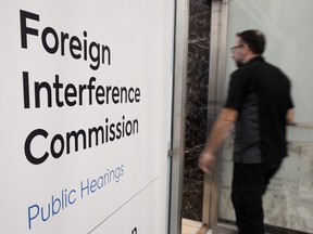 Blurred person walk past sign - Foreign Interfence Commission