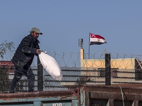 A worker carries bags of humanitarian aid that entered Gaza by truck through the Kerem Shalom (Karm Abu Salem) border crossing in the southern part of the Palestinian territory on Feb. 17, 2024, on the Palestinian side of the Rafah border crossing with Egypt on the southern Gaza Strip.