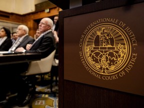 The Logo of the International Court of Justice (ICJ) is seen next to Minister of Foreign Affairs of the Palestinian Authority Riyad al-Maliki (right) and members of his delegation as they listen at the start of a hearing at the ICJ on the legal consequences of the Israeli occupation of Palestinian territories, in The Hague on Feb. 19, 2024.