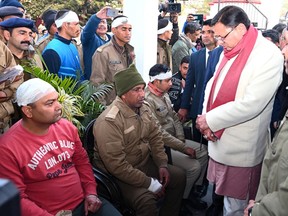 This photograph shared by Uttarakhand Chief Minister Pushkar Singh Dhami on his social media platform X shows him, right, in white jacket, meeting with the policemen injured in clashes over the construction of a Muslim seminary and a mosque in Haldwani in the Uttarakhand state, India, Friday, Feb. 9, 2024. (Pushkar Singh Dhami on X via AP)