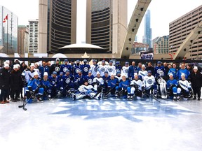 Members of the Toronto Maple Leafs and PWHL Toronto posing on ice at Nathan Phillips Square.
