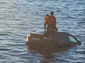 Two people stand atop of a car in the water after driving into the Oslofjord on Feb. 1, 2024 in Oslo.