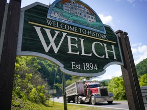 A coal truck drives past the welcome sign
