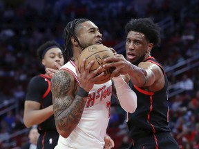 Houston Rockets forward Cam Whitmore, center, drives to the basket as Toronto Raptors forward Thaddeus Young, right, reaches in to block during the first half of an NBA basketball game Friday, Feb. 2, 2024, in Houston.