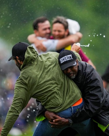 Canadian professional golfer Adam Hadwin is stopped by a security guard while he tries to celebrates with Nick Taylor after Taylor won the Canadian Open in 2023.