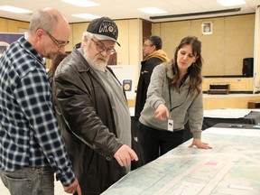 Kate Bondett with Ontario Northland, right, looks at a map of the future Timmins-Porcupine Station with local residents including John Brereton, centre. NICOLE STOFFMAN/POSTMEDIA