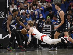 Toronto Raptors guard Gradey Dick passes the ball between Orlando Magic centre Wendell Carter Jr. (34) and Franz Wagner.