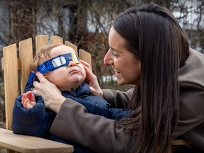 Emilie Alepin tries a pair of eclipse glasses on her 11-month-old son Leo Bartolone at their home in the LaSalle borough of Montreal Wednesday, March 20, 2024.