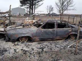 The remains of a car sit in ashes.