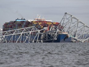 The steel frame of the Francis Scott Key Bridge sits on top of a container ship after the bridge collapsed collapsed in Baltimore, Md., March 26, 2024.