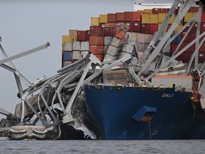 The steel frame of the Francis Scott Key Bridge sits on top of the container ship Dali after the bridge collapsed in Baltimore, Md., on Tuesday, March 26, 2024.