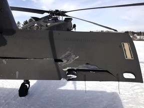 a damaged Black Hawk helicopter rests on the snow