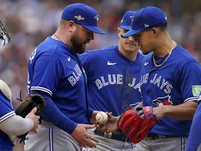 Toronto Blue Jays manager John Schneider, left, takes the ball from pitcher Jose Berrios during a pitching change in the fourth inning of Game 2 of an AL wild card baseball playoff series against the Minnesota Twins on Wednesday, Oct. 4, 2023, in Minneapolis.