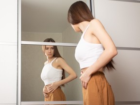 Teenage girl looks in the mirror and is unhappy with what she sees.