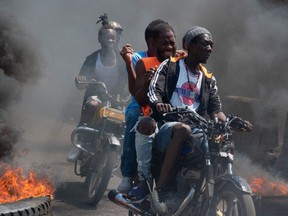 Men on motorcycles ride past burning tires during a demonstration following the resignation of its Prime Minister Ariel Henry, in Port-au-Prince, Haiti, Tuesday, March 12, 2024.