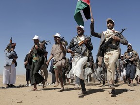 Houthi fighters march during a rally
